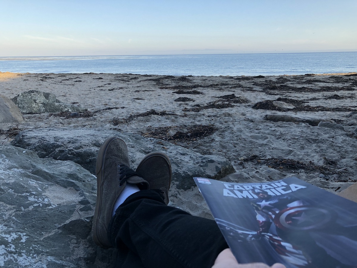 1st person photo of me holding a copy of Captain America (2018) #2 on the beach